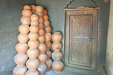 Potter's house porch, wooden front door and piles of clay pots stacked against the wall, near Rayagada, Orissa, India, Asia