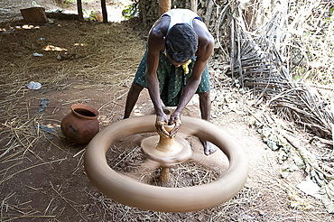 Village potter forming hand made clay pot on potter's wheel spinning in his village workshop, near Rayagada, Orissa, India, Asia