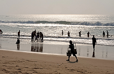 Puri beach on the Bay of Bengal, Indian families relaxing and paddling, beach vendor walking by in the late afternoon, Puri, Orissa, India, Asia