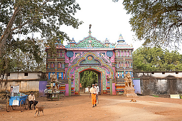 Ascetics walking through ornately carved and painted entrance to Joranda monastery complex, Joranda, Orissa, India, Asia