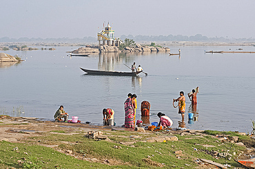 Women performing early morning ablutions in the River Mahanadi, men in fishing boat passing by, Vaidyanathpur, Orissa, India, Asia