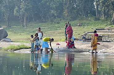 Women washing clothes on the ghats of the  River Mahanadi, reflected in the water, Orissa, India, Asia