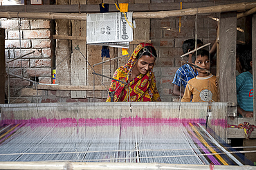 Village woman working on domestic loom with her children looking on, rural West Bengal, India, Asia