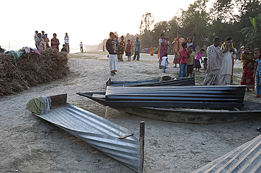 Villagers surrounding small boats made from single sheets of corrugated iron, lying on the banks of the River Hugli (River Hooghly), West Bengal, India, Asia