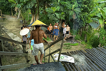 Iban tribal chief joins other villagers sharing a joke and cooking in the rain, Lemanak River, Sarawak, Malaysian Borneo, Malaysia, Southeast Asia, Asia