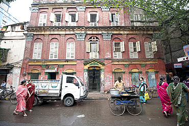 Street snack seller with his wheeled stall outside beautiful old Raj era building in Kolkata back street, West Bengal, India, Asia