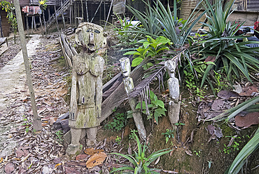 Carved spirits of men and a woman standing at the entrance to Iban tribal longhouse at Ngemah beach on the Lemanak River, Sarawak, Malaysian Borneo, Malaysia, Southeast Asia, Asia