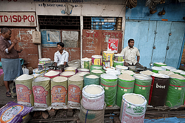 Rice wallahs sitting behind full sacks of rice waiting for customers in the early morning, New Market, Kolkata, West Bengal, India, Asia