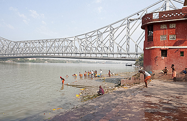 Men performing ablutions on ghats beneath the Howrah Bridge in the early morning, Kolkata (Calcutta), West Bengal, India, Asia