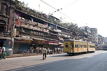 Yellow Kolkata tram passing Kolkata slums in the early morning, Kolkata, West Bengal, India, Asia