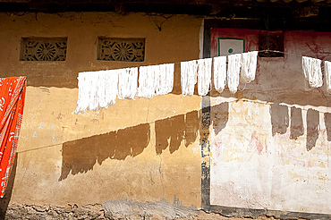 Skeins of washed spun raw silk hanging to dry along a village house wall, Naupatana village, Orissa, India, Asia