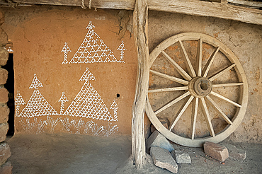 Village house wall with typical Orissa rice flour painting, and wooden cartwheel, Naupatana weaving village, rural Orissa, India, Asia