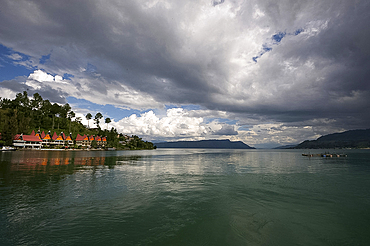 Monsoon clouds gathering over hotel on the edge of the still waters of volcanic Lake Toba, Sumatra