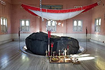 Holy rock from the Brahmaputra, painted black, in the centre of village Shiva temple on the banks of the Brahmaputra, Assam, India, Asia