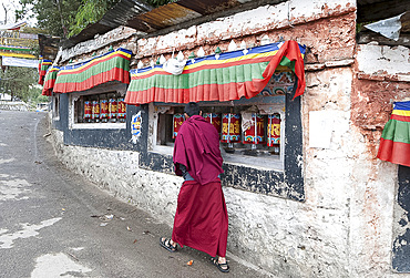 Buddhist monk turning prayer wheels outside Tawang Buddhist monastery, Arunachal Pradesh, India, Asia