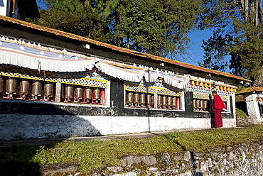 Buddhist monk in red robes turning prayer wheels in contemplative morning prayer, Tawang Buddhist monastery, Arunachal Pradesh, India, Asia