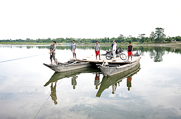 Villagers and a motorbike on a ferry made from two wooden boats and wooden platform, pulled across the Brahmaputra river, Assam, India, Asia