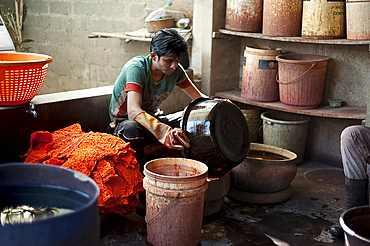 Dye worker cleaning pots in small bhandani tie-dye workshop, Mandvi, Gujarat, India, Asia