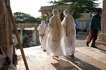 Jain pilgrims in white robes, returning back down Shatrunjaya Hill after walking up to Jain shrines at dawn, Palitana, Gujarat, India, Asia