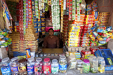 Man in his small local shop selling piled up biscuits and sweets in rural town, Dhenkanal district, Orissa (Odisha), India, Asia