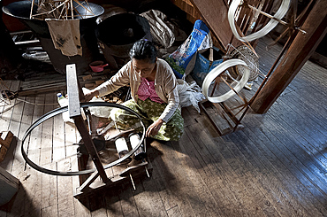 Woman spinning silk thread on a spinning wheel with bicycle wheel, Ko Than hlaing Weaving, Inpawkhan, Inle Lake, Shan state, Myanmar (Burma), Asia