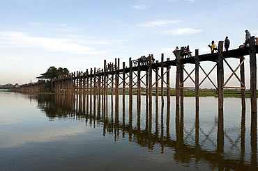 People crossing U Bein's Bridge, supported by 984 teak posts over 1.2 km distance across Thaumthaman Lake, Mandalay, Myanmar (Burma), Asia