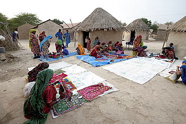 Pathan village people, women showing their traditional embroideries in front of mud and thatched tribal houses, Jarawali, Kutch, Gujarat, India, Asia