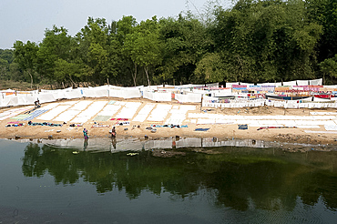 Dhobi wallahs, a man and a woman, hand washing clothes in the river, laundry laid out to air dry, Bhargabi River, Odisha, India, Asia