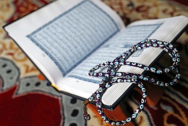 Holy Quran in Arabic and Muslim prayer beads on wood stand, Vietnam, Indochina, Southeast Asia, Asia