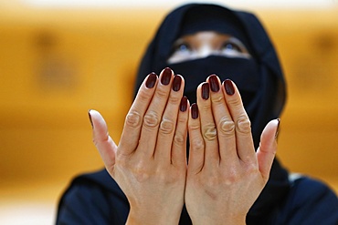 Muslim woman in abaya prays with her hands raised, United Arab Emirates, Middle East