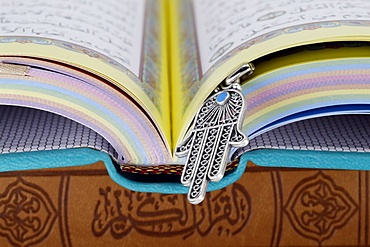 Open Holy Quran with Hamsa (Hand of Fatima) symbols of Muslim faith and religion, France, Europe