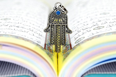 Open Holy Quran with Hamsa (Hand of Fatima) symbols of Muslim faith and religion, France, Europe