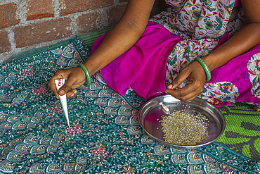 Adivasi woman sticking beads onto a sari in a village in Narmada district, Gujarat, India, Asia