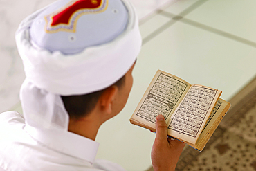 Muslim man reading an Arabic Holy Quran (Koran), Jamiul Azhar Mosque, Vietnam, Indochina, Southeast Asia, Asia