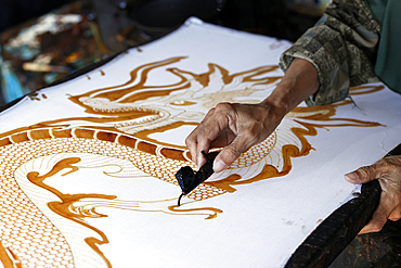 Batik Production. Woman using hot wax to outline a dragon design. Yogyakarta. Indonesia.