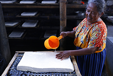 Worker making tofu in a traditional family factory. Tofu is a food prepared by coagulating soy milk. Yogyakarta. Indonesia.