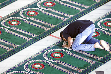 Al Akbar Surabaya National Mosque. Muslim man praying and whorship on carpet with arches designed to point towards Mecca.. Surabaya. Indonesia.