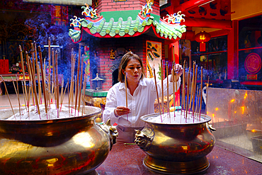 Guan Di chinese Temple in Chinatown. Offerings and prayer to the temple deities. Asian woman praying. Kuala Lumpur. Malaysia.