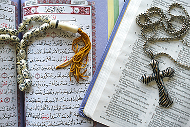 Holy Quran with a muslim prayer beads and bible with rosary. Interfaith symbols between Christianity and Islam.