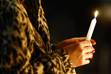 Catholic woman lighting a candle in a church to pray. Warsaw. Poland.