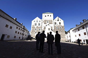 Men silhoutted against Turku Medieval Castle, Turku, Western Finland, Finland, Scandinavia, Europe