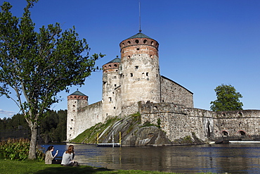 Girls relaxing beside Olavinlinna Medieval Castle (St. Olaf's Castle), Savonlinna, Saimaa Lake District, Savonia, Finland, Scandinavia, Europe