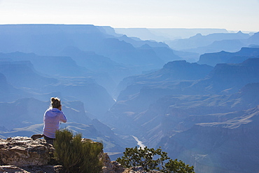 Woman sitting on the cliff of the desert view point over the Grand Canyon, UNESCO World Heritage Site, Arizona, United States of America, North America