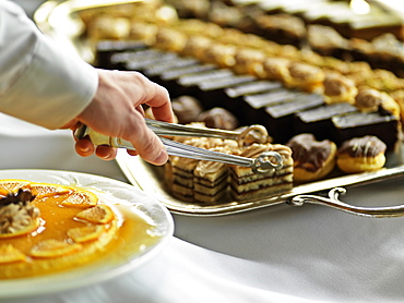 Dessert tray with hand and tongs reaching for pastry, Jasper Park Lodge, Jasper, Alberta, Canada, North America