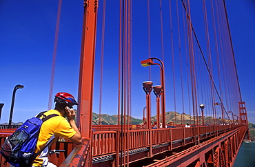 Cyclist using cell phone on the Golden Gate Bridge, San Francisco, California, United States of America, North America