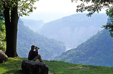 Young woman enjoying view of gorge with camera in hand, Letchworth State Park, New York State, United States of America, North America