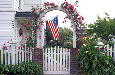 Gate to house with roses framing a US flag, Mendocino, California, United States of America, North America