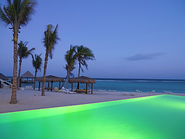 Infinity pool illuminated by the edge of a beach with the sea in the background, Mayan Riviera, Akumal, Yucatan, Quintana Roo, Mexico, North America