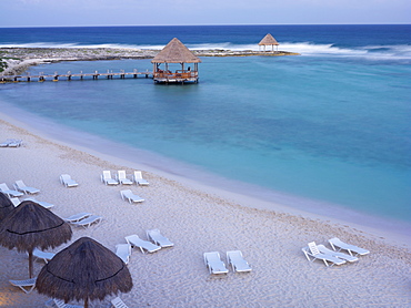 Mexico, Quintana Roo, Yucatan Peninsula, Akumal, Mayan Riviera, beach chairs and palapas on a beach by the sea