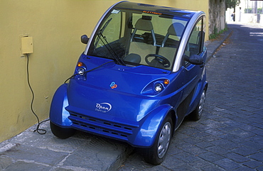 Electric car being charged at wall outlet, Florence, Tuscany, Italy, Europe